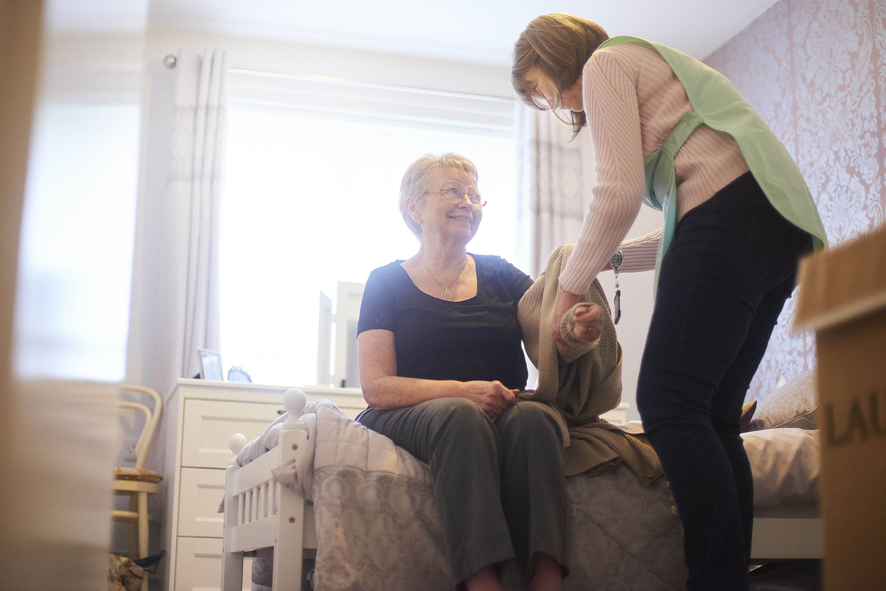 A female health worker helps dress and elderly woman